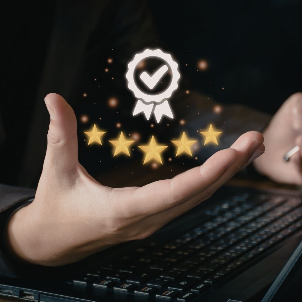 Symbol für Qualitätssiegel mit fünf goldenen Sternen über einer Hand auf einer Tastatur.