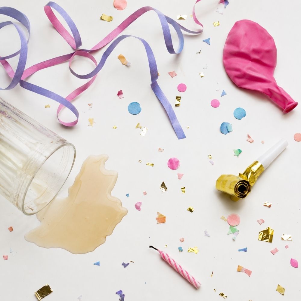 EinladungFlat-Lay einer chaotisch misslungenen Partyplanung mit defektem Ballon, Kerze und verschüttetem Getränk
